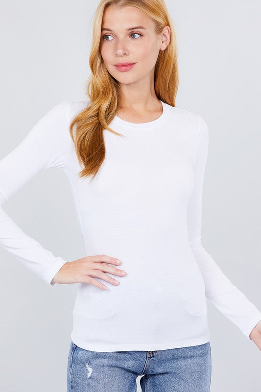 Woman wearing a white long-sleeve top and blue jeans against a plain background