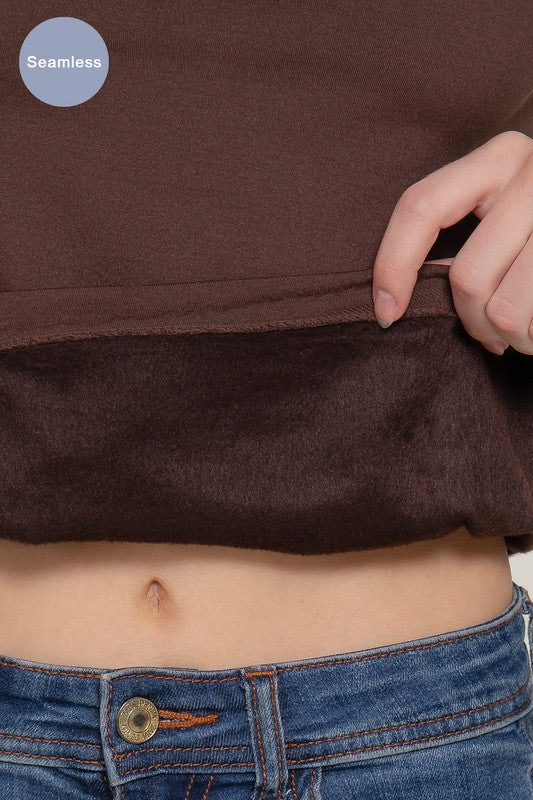 Brown cropped top being worn with blue jeans, showing a close-up of the waistband.