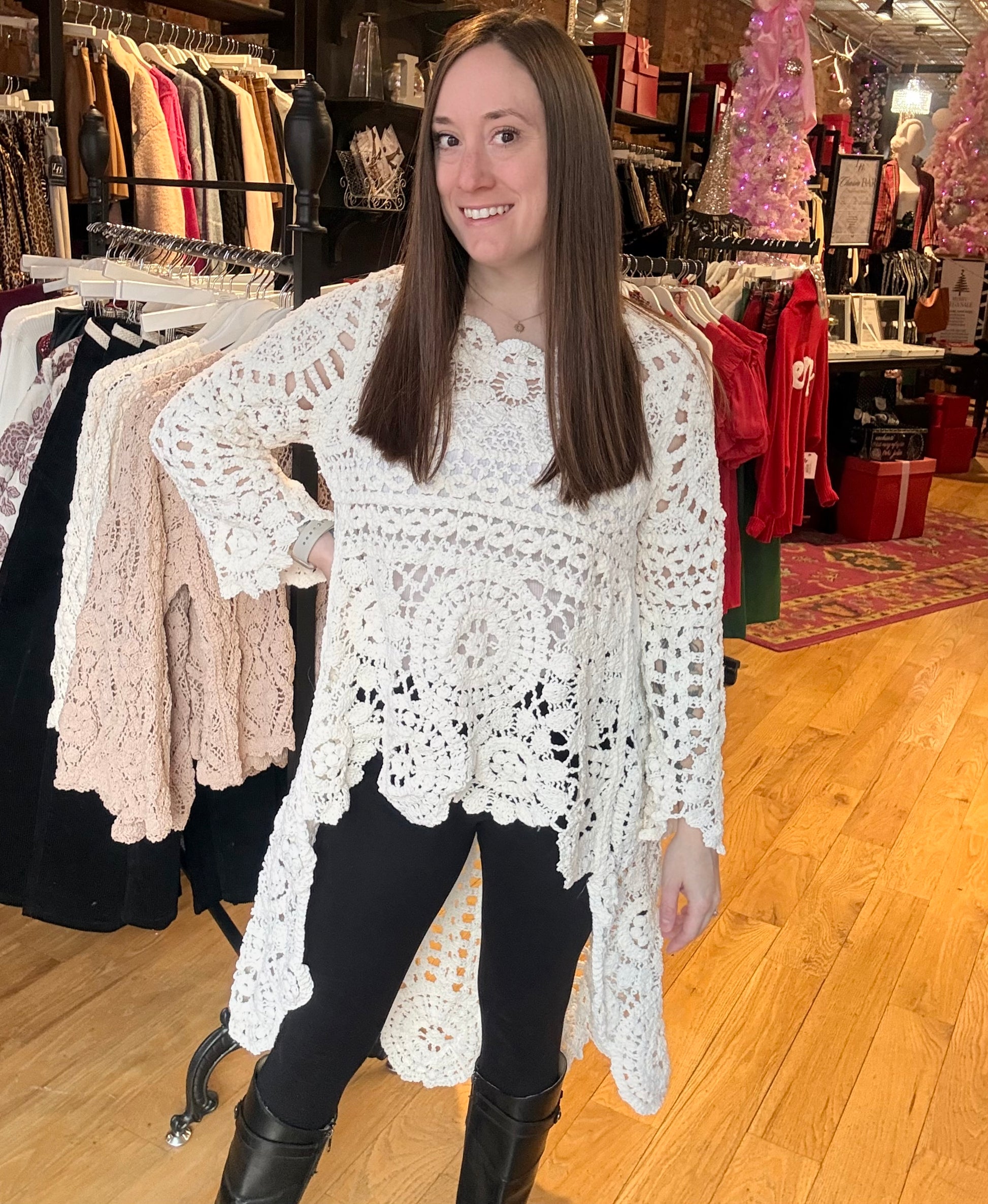 Woman wearing a white lace top in a clothing store.