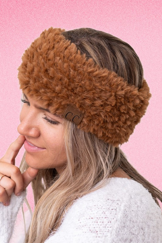 Woman wearing a brown fur headband with a pink background