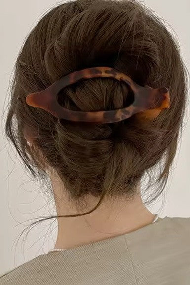 Person with a tortoiseshell hair clip in their bun against a plain background