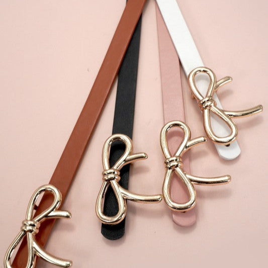 Gold bow-shaped belts on a pink background