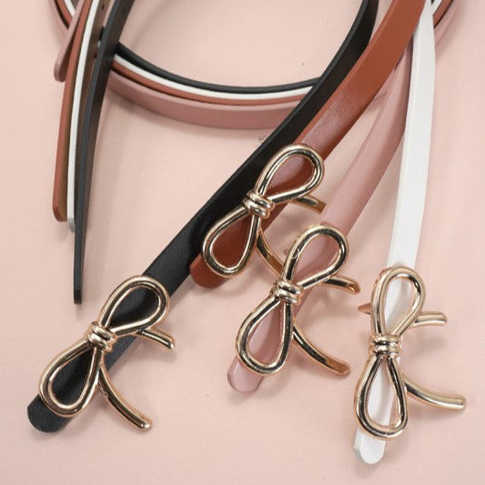 Gold bow-shaped belts on a pink background