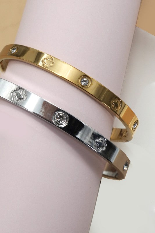 Two gold and silver bracelets on a pink surface