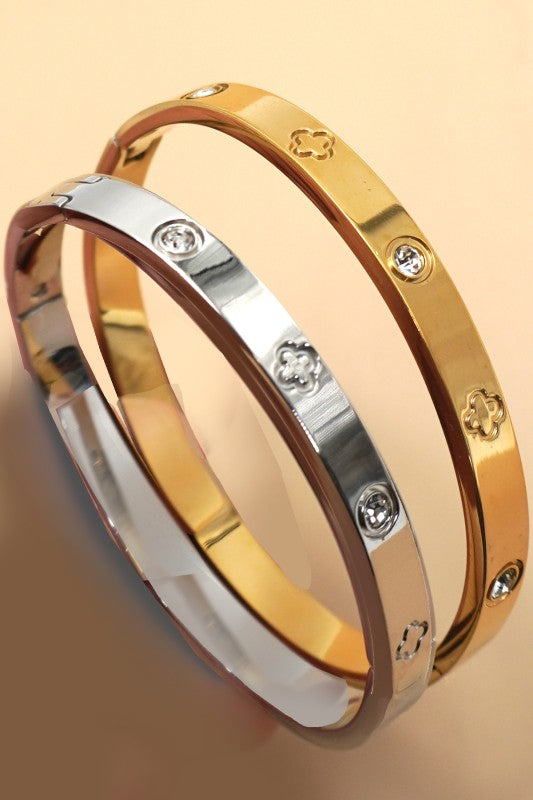Three gold bracelets with diamond accents on a beige background