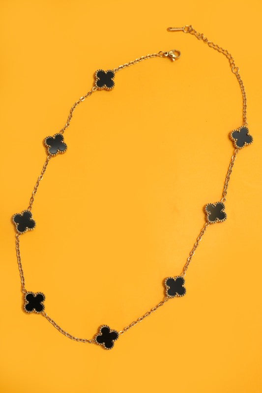 Necklace with black clover-shaped pendants on a yellow background