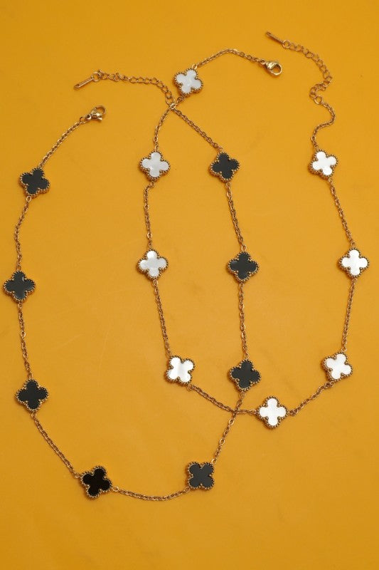 Necklace with clover-shaped pendants on a mustard yellow background