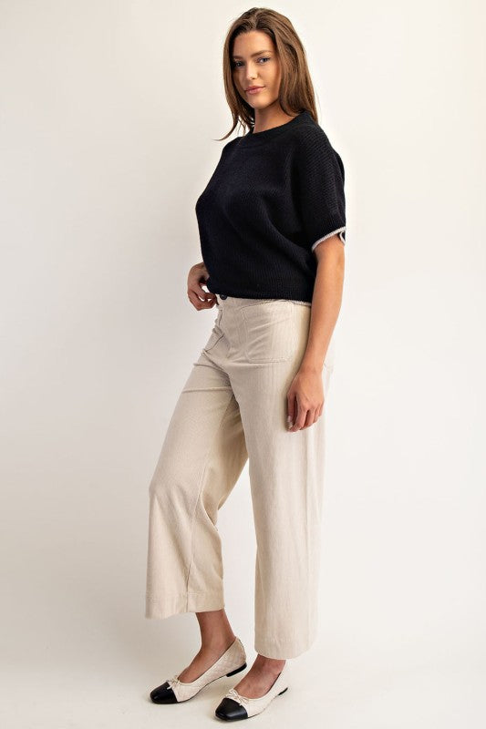 Woman wearing a black top and beige pants on a white background