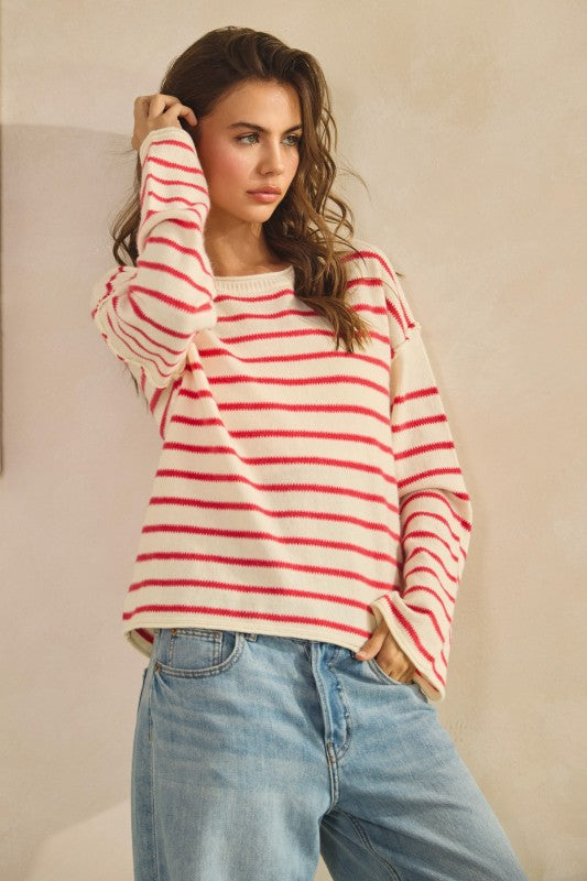 Woman wearing a red and white striped sweater and blue jeans against a beige background