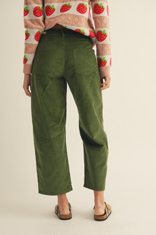Person wearing green pants and a patterned top on a beige background