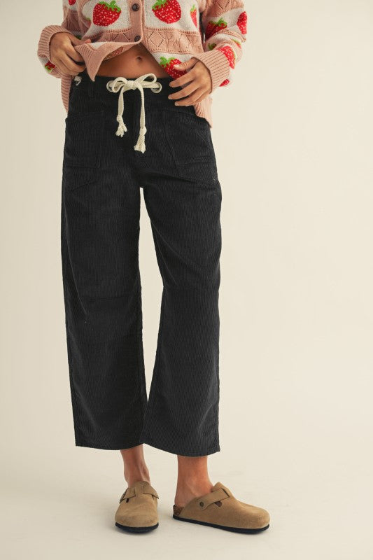 Person wearing black wide-leg pants with a beige background