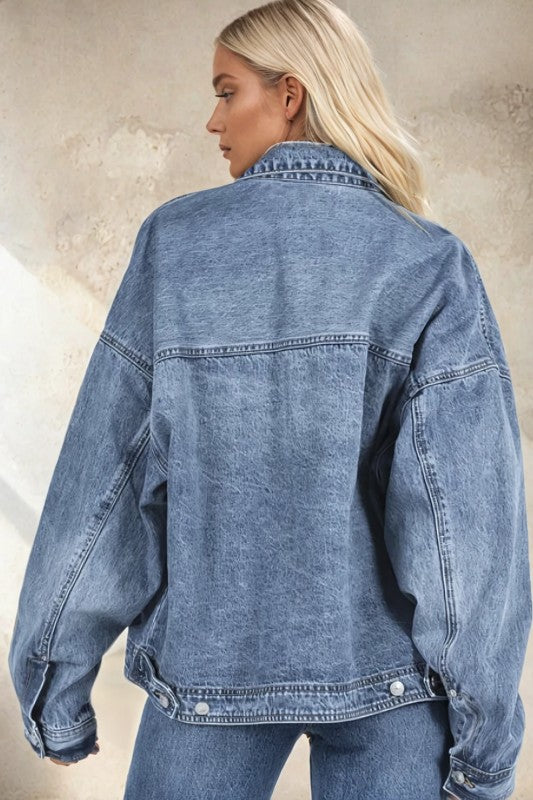 Person wearing a blue denim jacket against a neutral background