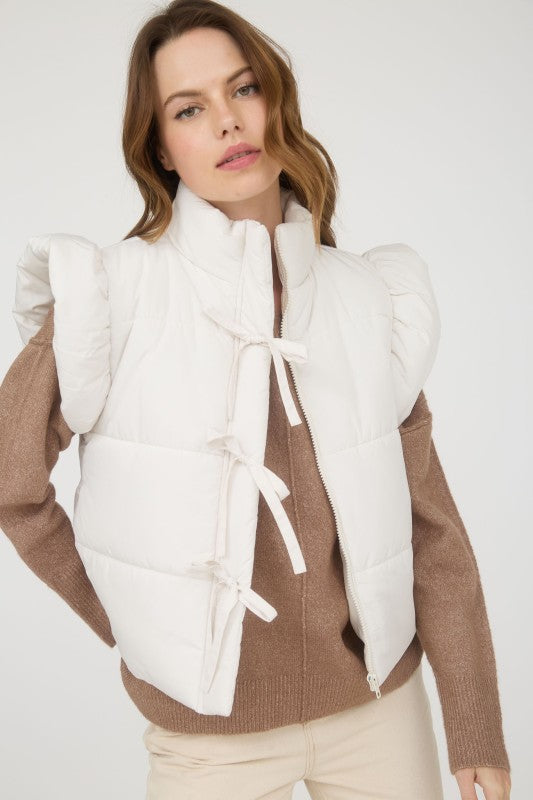 Woman wearing a brown sweater with a white puffer vest on a white background