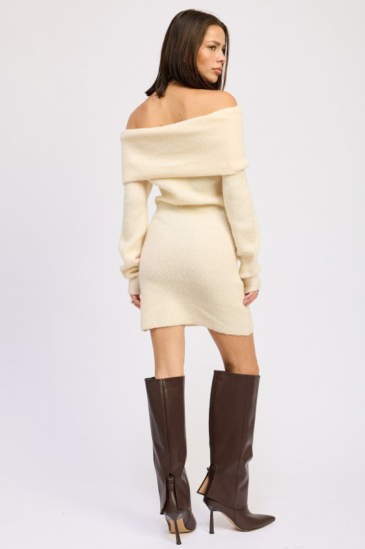 Woman wearing a cream off-shoulder sweater dress with brown knee-high boots on a white background