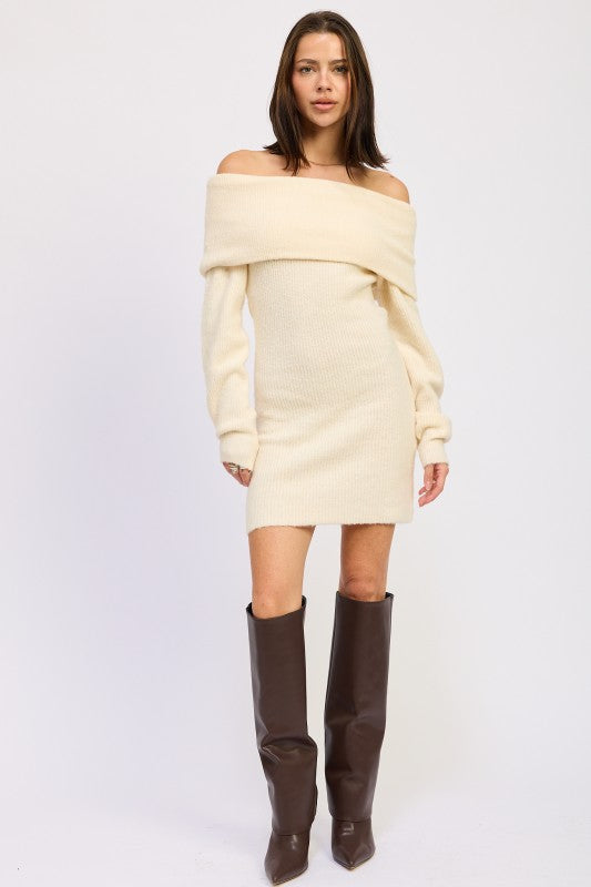 Woman wearing a cream off-shoulder sweater dress with brown knee-high boots on a white background