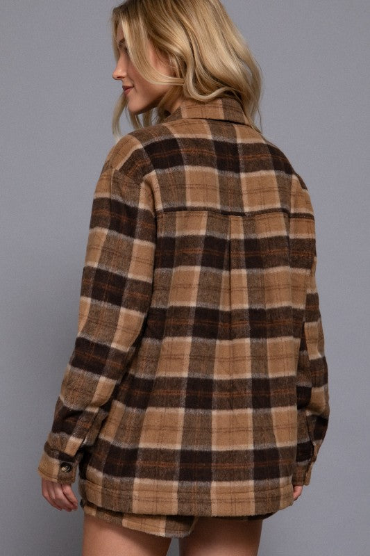 Person wearing a brown and beige plaid shirt against a gray background