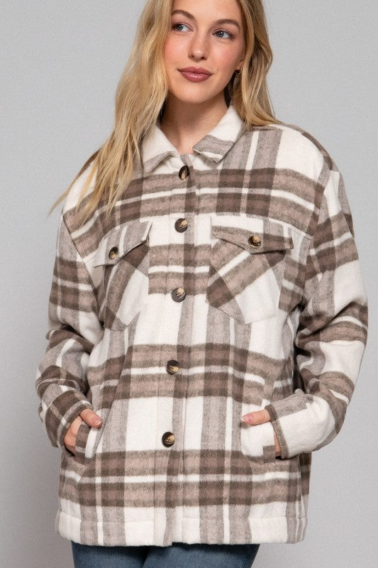 Woman wearing a plaid jacket with a neutral background