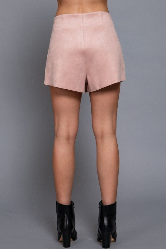 Pink suede skirt worn by a person on a gray background