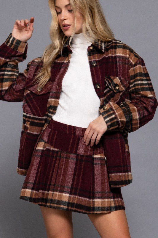 Woman wearing a plaid jacket and skirt set against a gray background