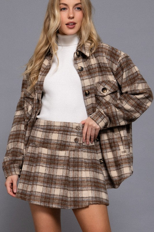 Woman wearing a plaid jacket and skirt set against a gray background