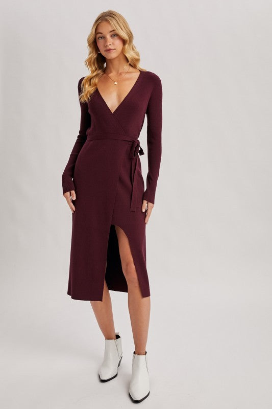 Woman wearing a burgundy dress with long sleeves and a slit on a white background