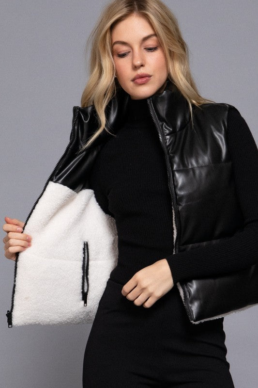 Woman wearing a black leather vest with white fur lining against a gray background