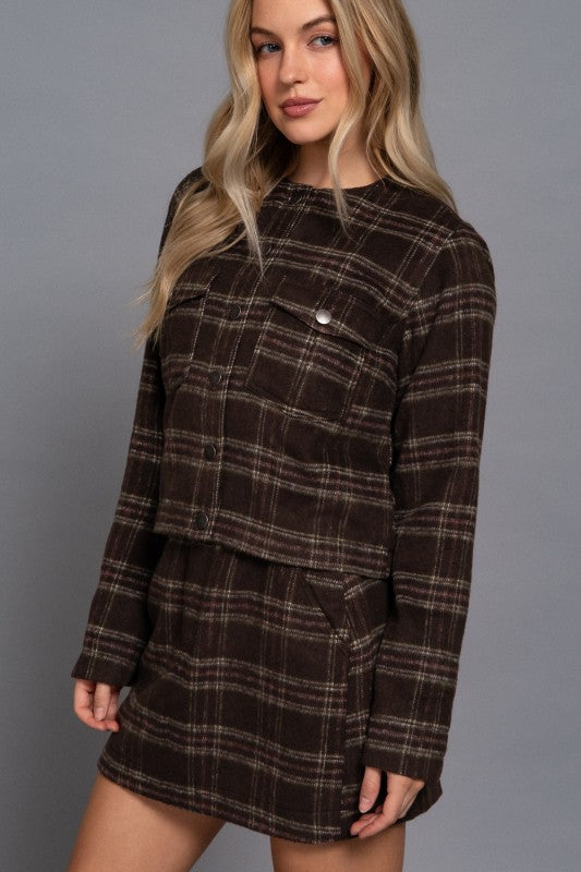 Woman wearing a brown plaid dress against a gray background