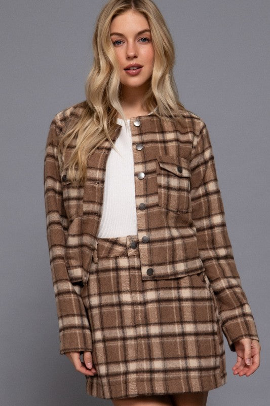 Woman wearing a brown plaid coat against a gray background