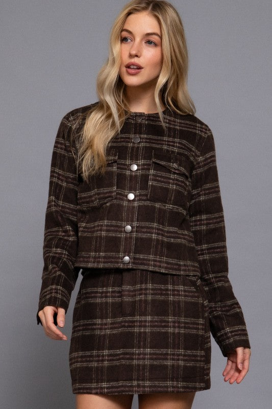 Woman wearing a brown plaid dress against a gray background