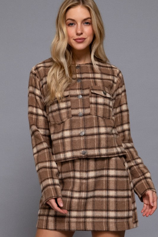 Woman wearing a brown plaid dress against a gray background