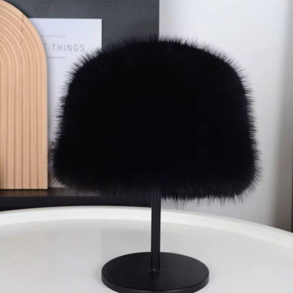 Black fur hat on a stand against a neutral background