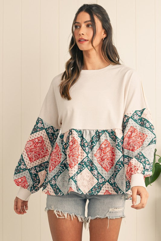 Woman wearing a white top with patterned sleeves against a neutral background