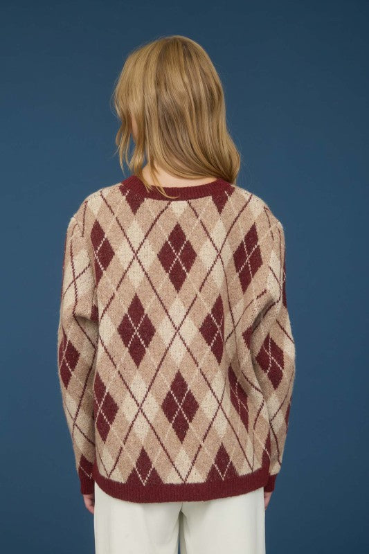 Person wearing a patterned sweater against a blue background
