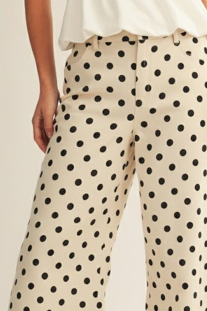 Beige pants with black polka dot pattern worn by a person.