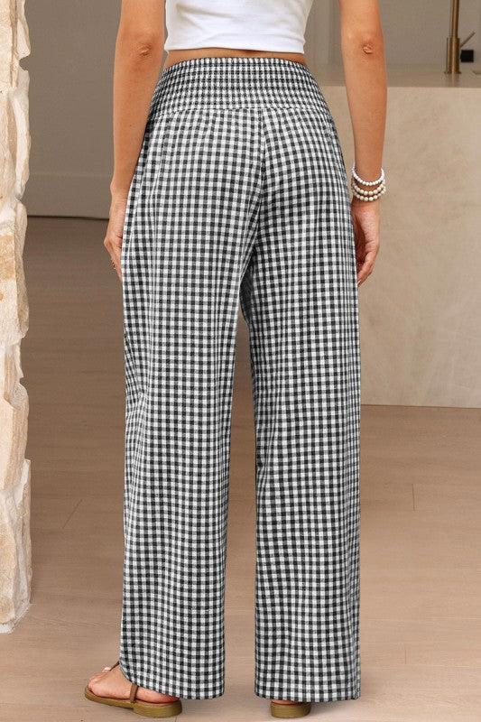 Person wearing black and white checkered pants in a neutral setting