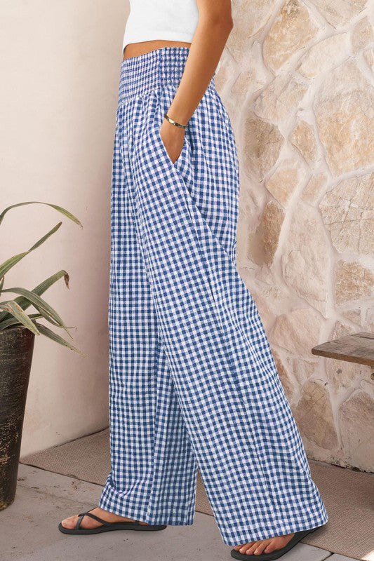 Person wearing blue and white checkered pants standing against a stone wall.