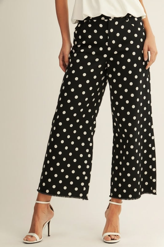 Black polka dot pants worn by a person on a plain background