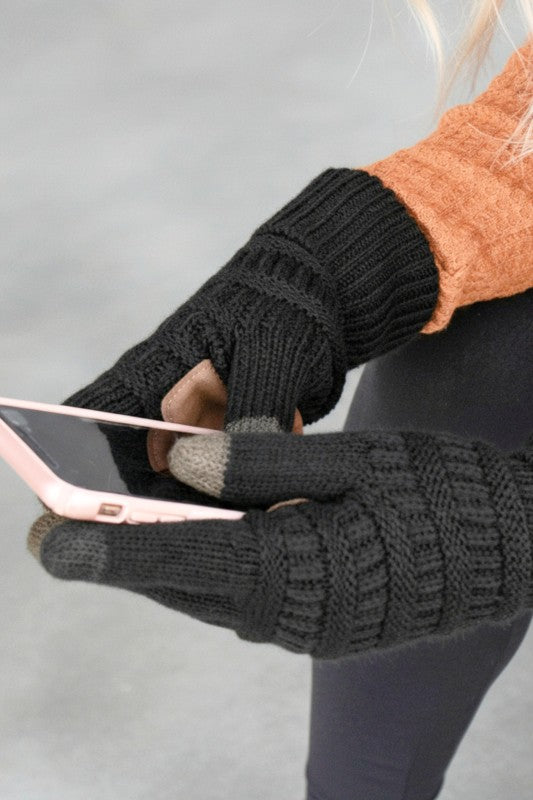 Person wearing black fingerless gloves using a smartphone with a blurred background