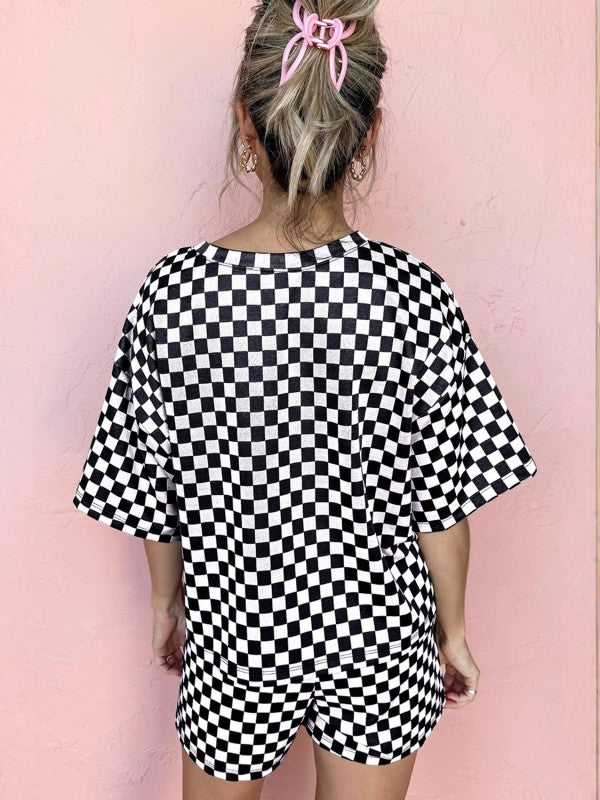 Person wearing a black and white checkered outfit against a pink background