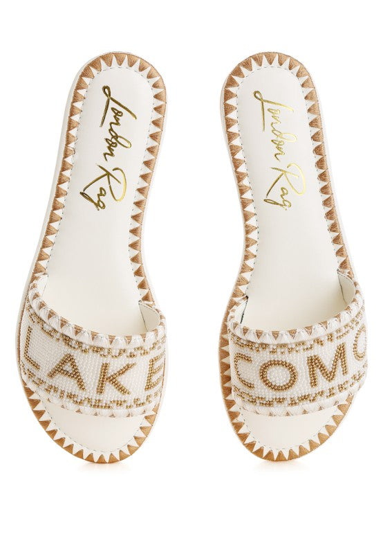 Pair of white sandals with gold text on a white background