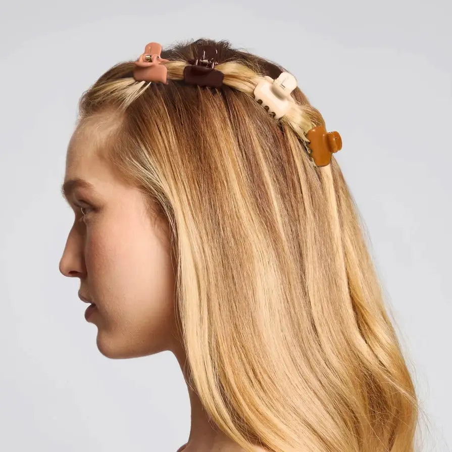 Woman with colorful hair clips in her blonde hair against a light gray background