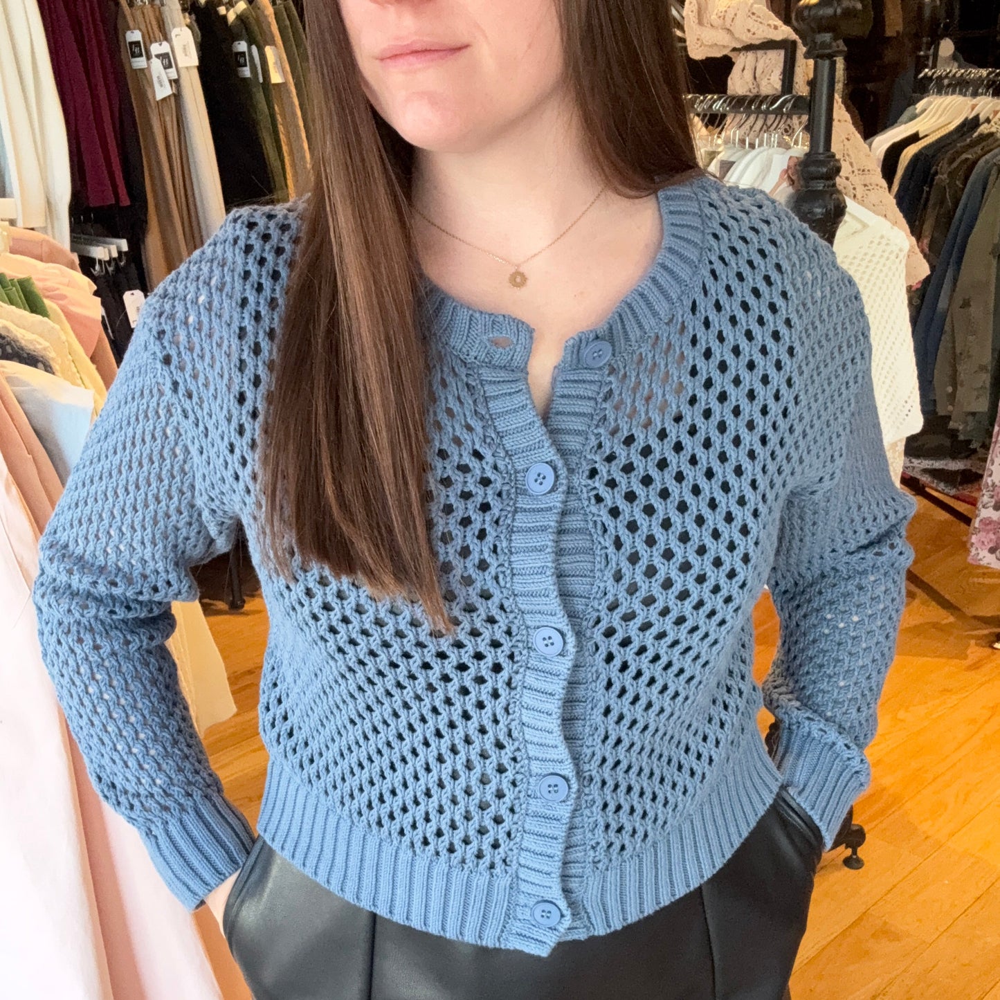 Woman wearing a blue knitted cardigan in a store setting
