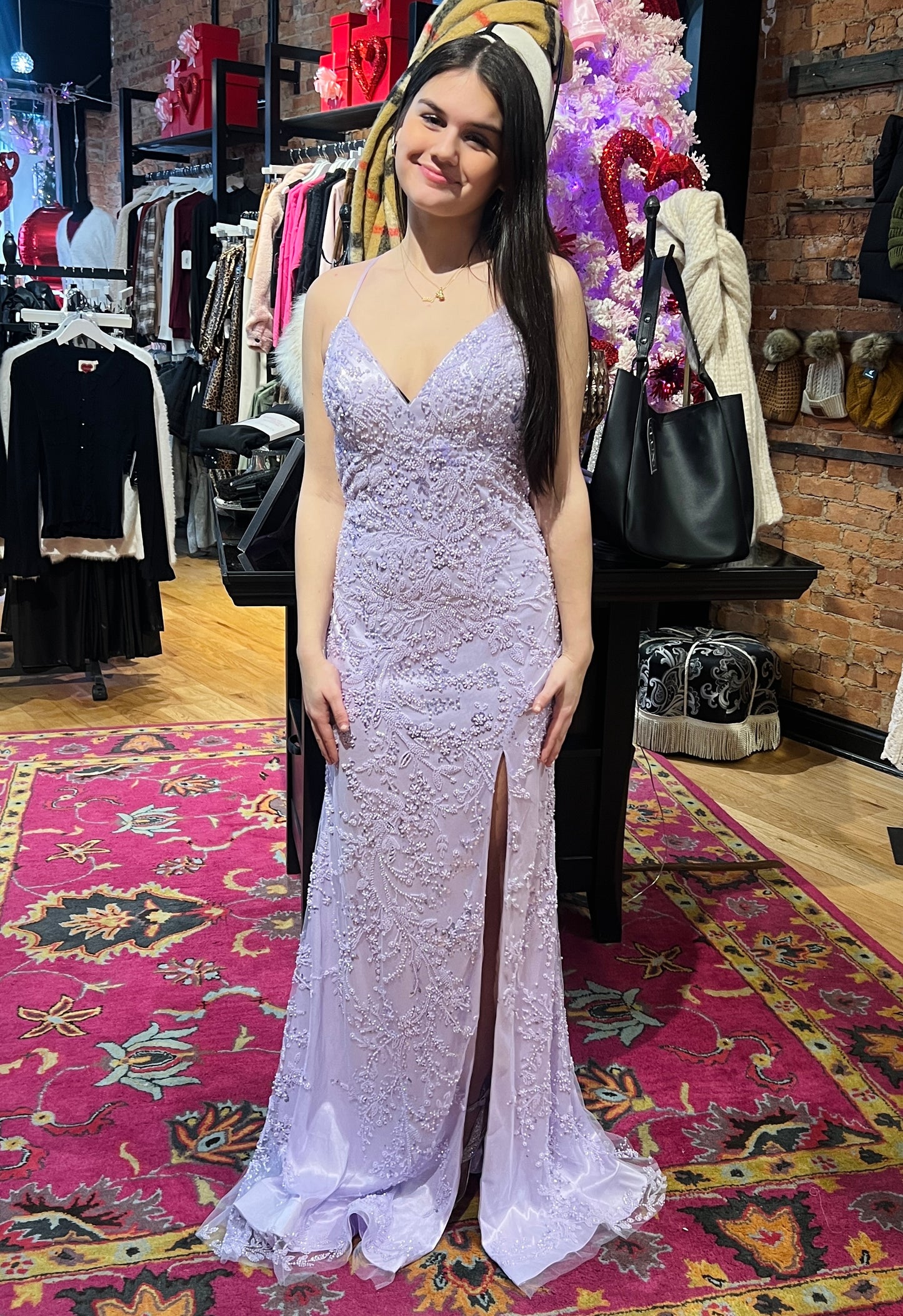 Woman in a purple lace dress standing in a store with colorful decorations.