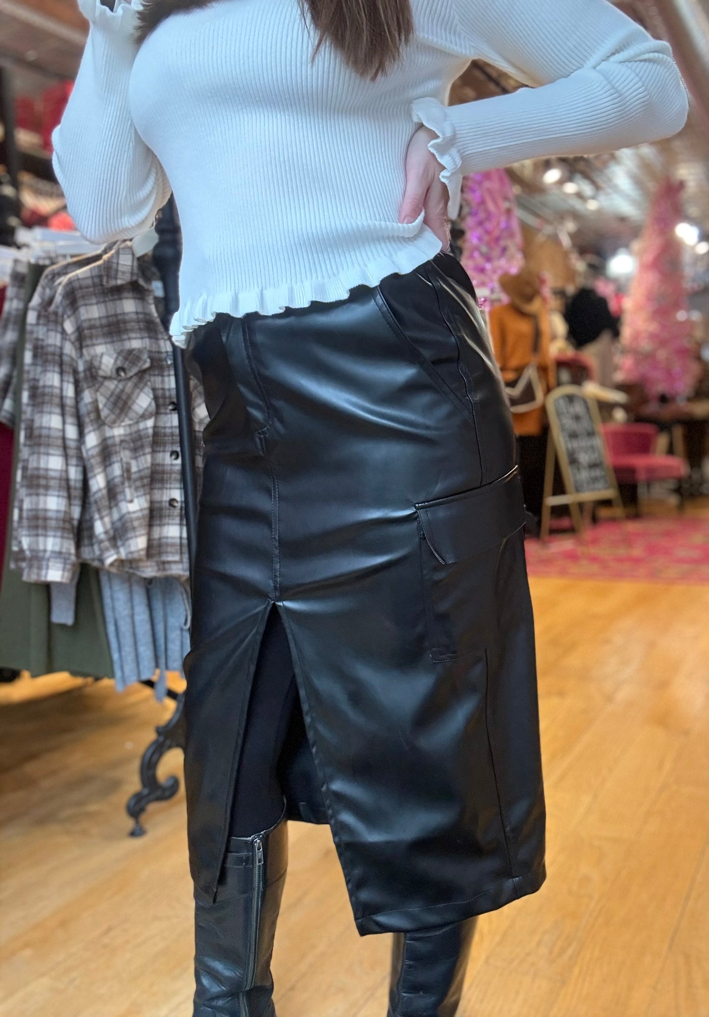 Person wearing a white top and black leather skirt in a store setting