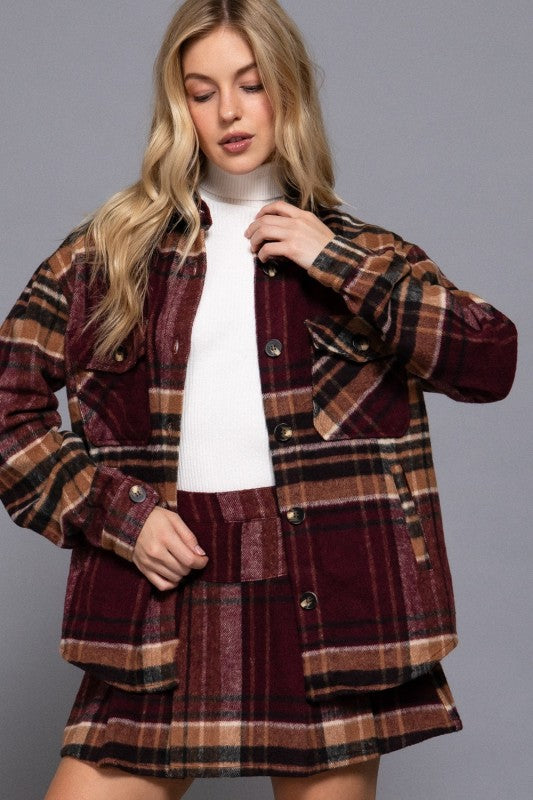 Woman wearing a plaid jacket and skirt set against a gray background
