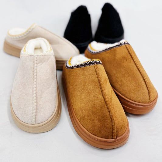 Pair of tan and beige slippers on a light gray background