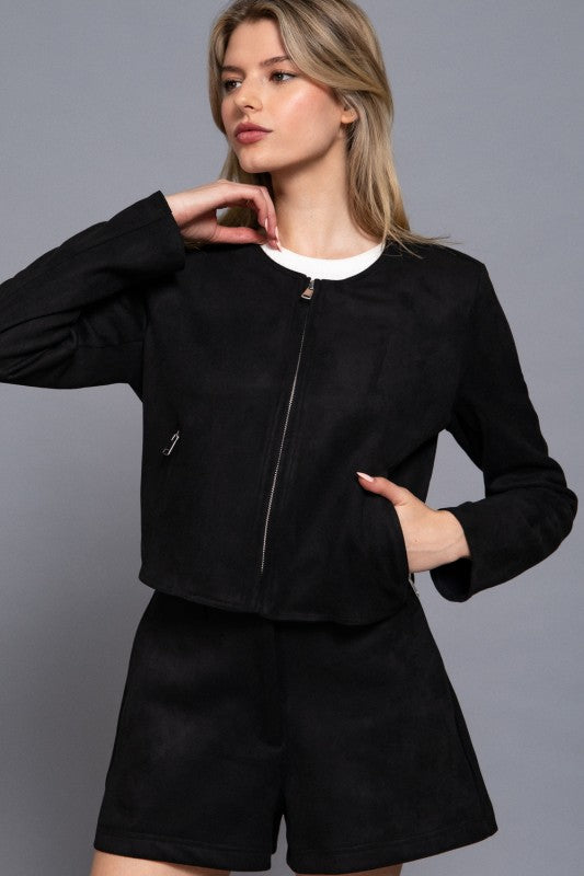 Woman wearing a black jacket and shorts set on a gray background