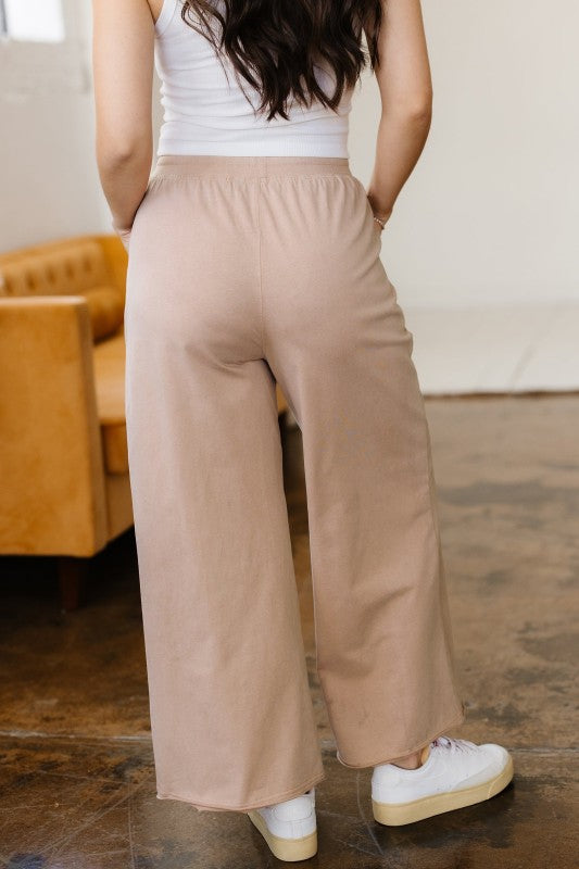 Person wearing beige wide-leg pants and a white top in an indoor setting.