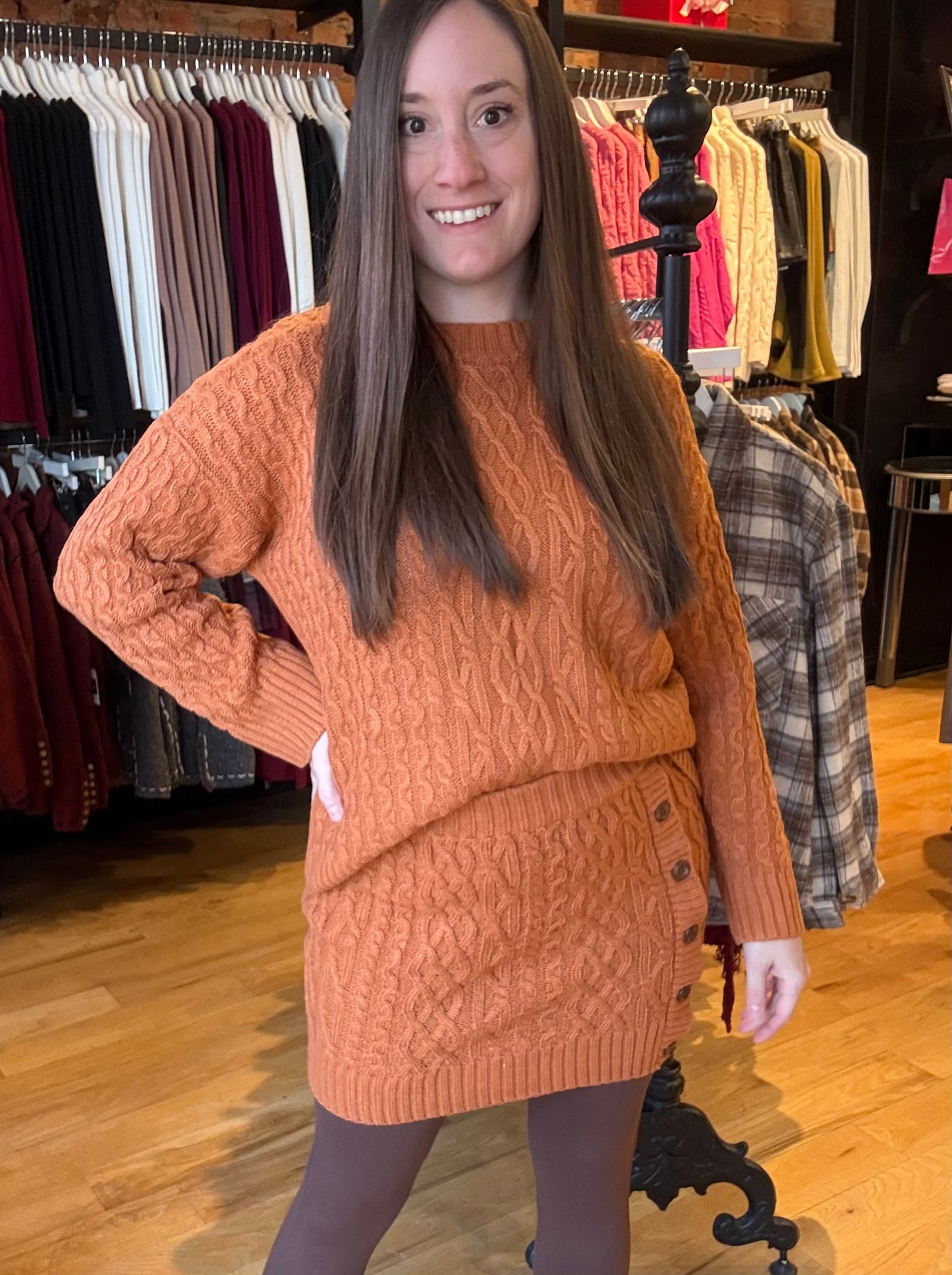 Woman wearing a brown cable knit sweater dress in a clothing store.