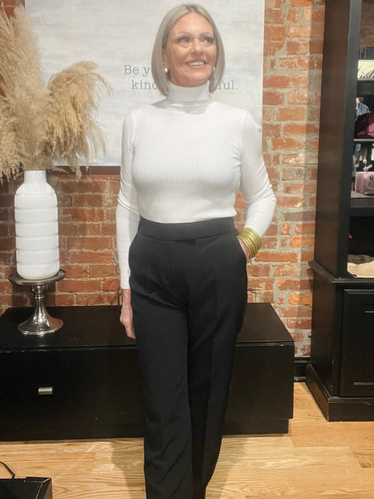Woman wearing black trouser pants with a white turtleneck sweater